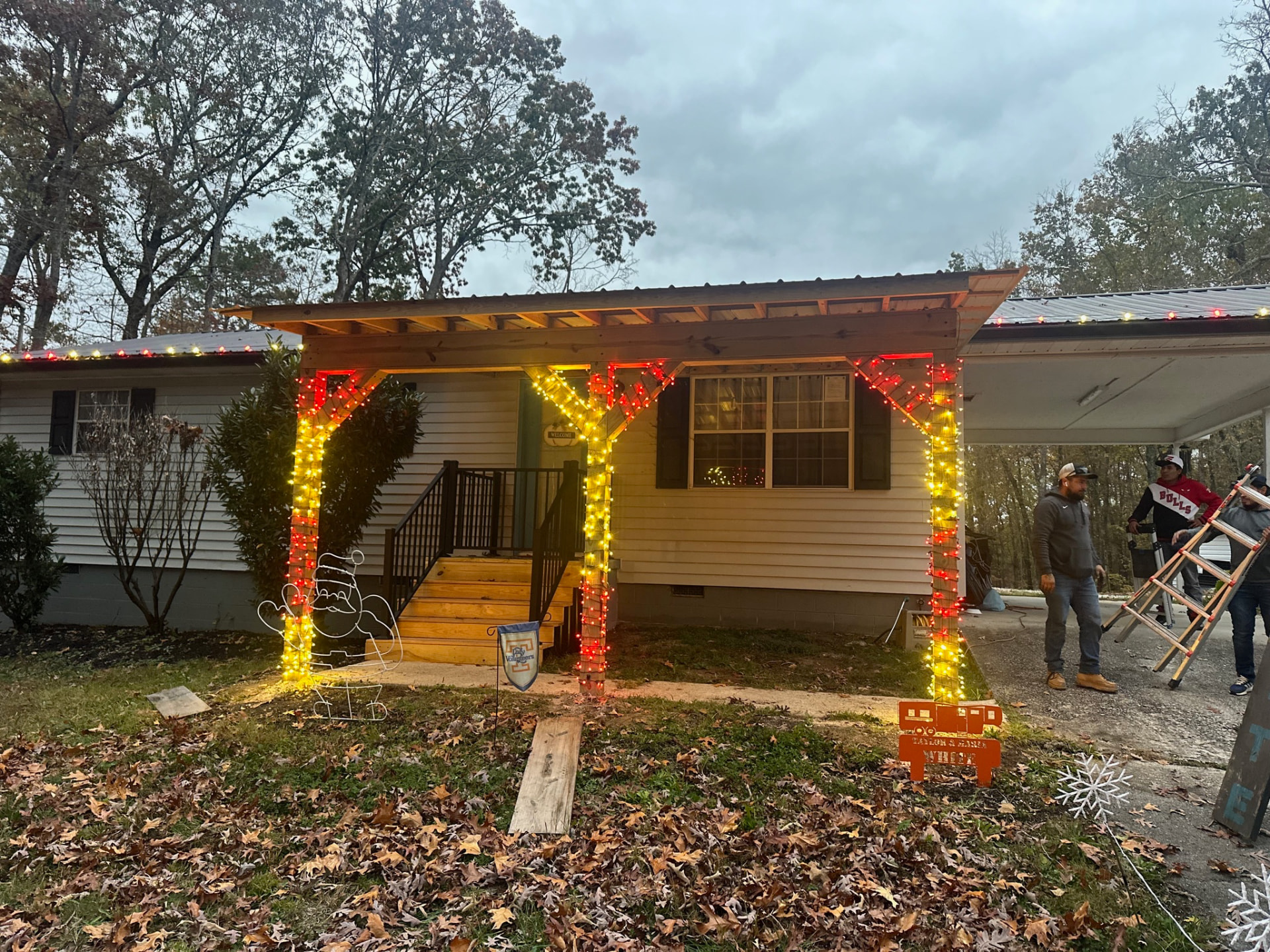 Installation crew with ladders lighting porch posts in red and gold Christmas lights at a Blount County TN home