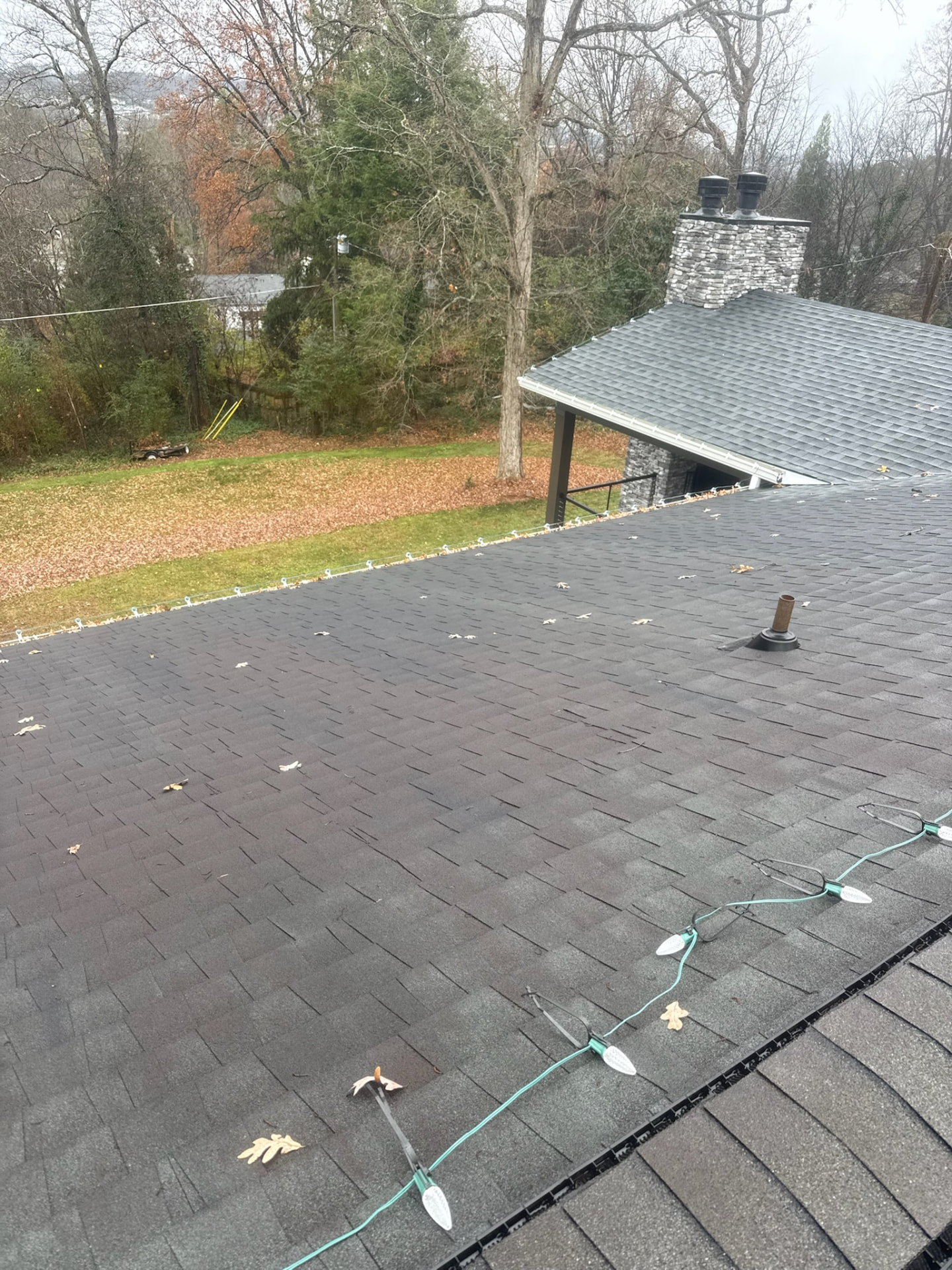 Christmas light strand attached to a shingle roof edge with non-penetrating clips during installation in Maryville TN