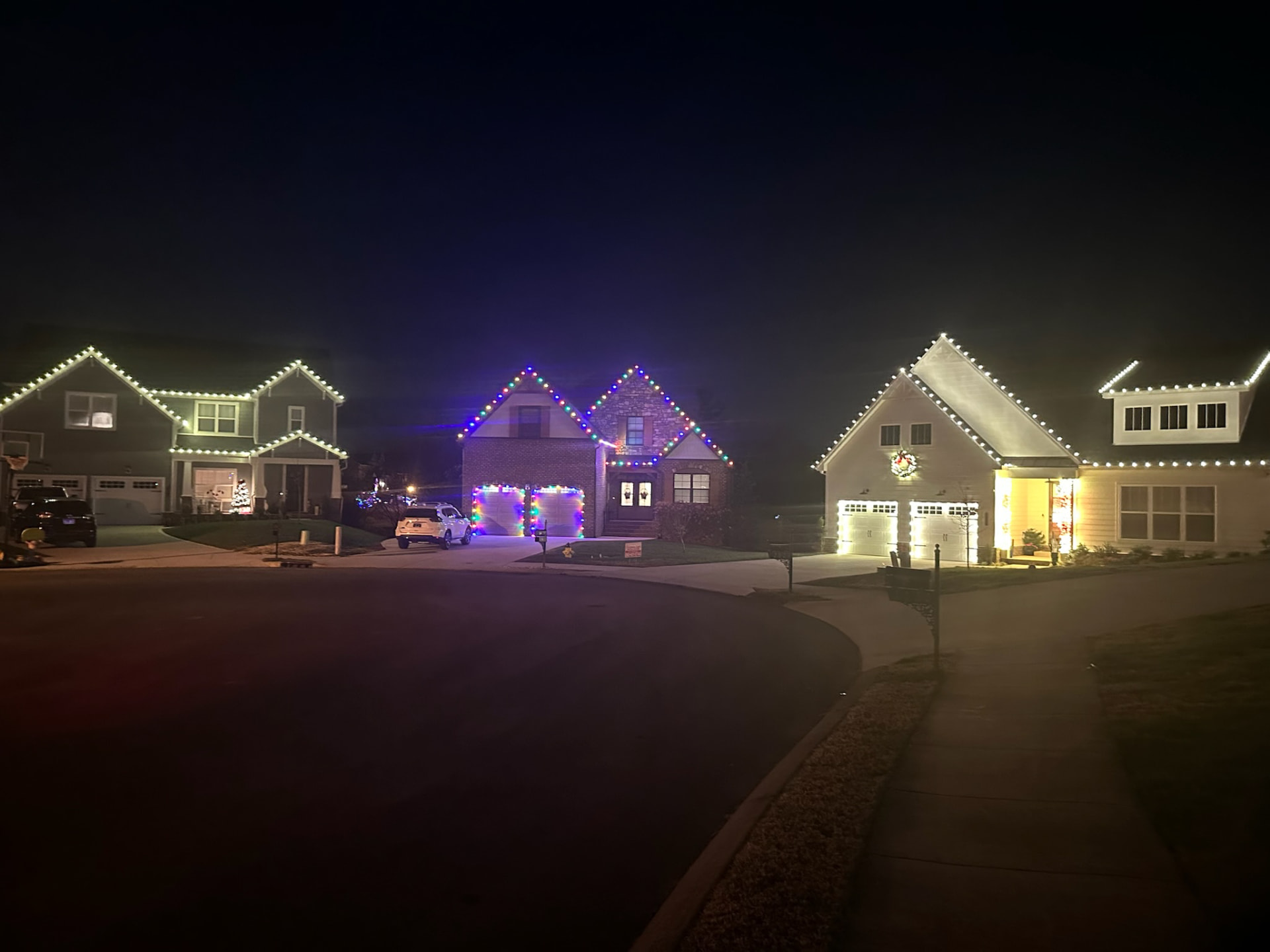 Several neighboring homes in a Maryville TN cul-de-sac all lit with professionally installed Christmas lights on the rooflines